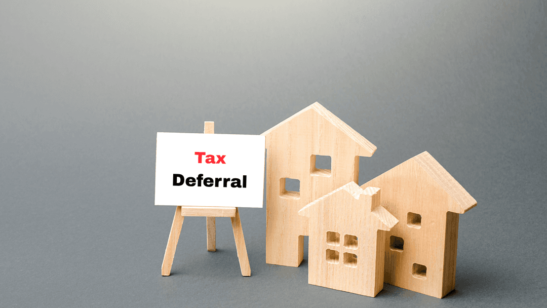 Three wooden home models grouped near a tax deferral board