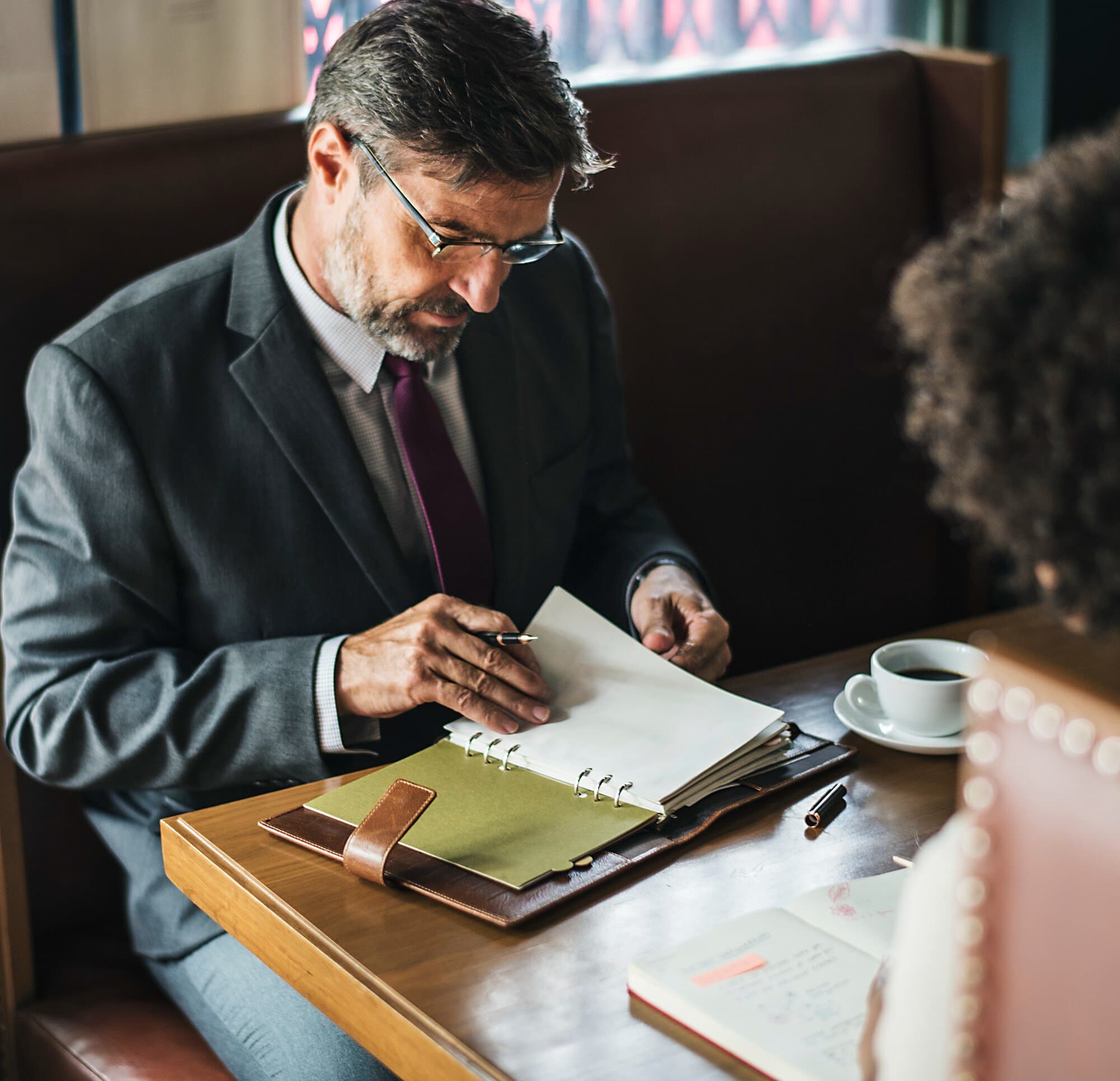Residential property tax consultant reviewing client tax documents and notes in a binder during a consultation meeting.