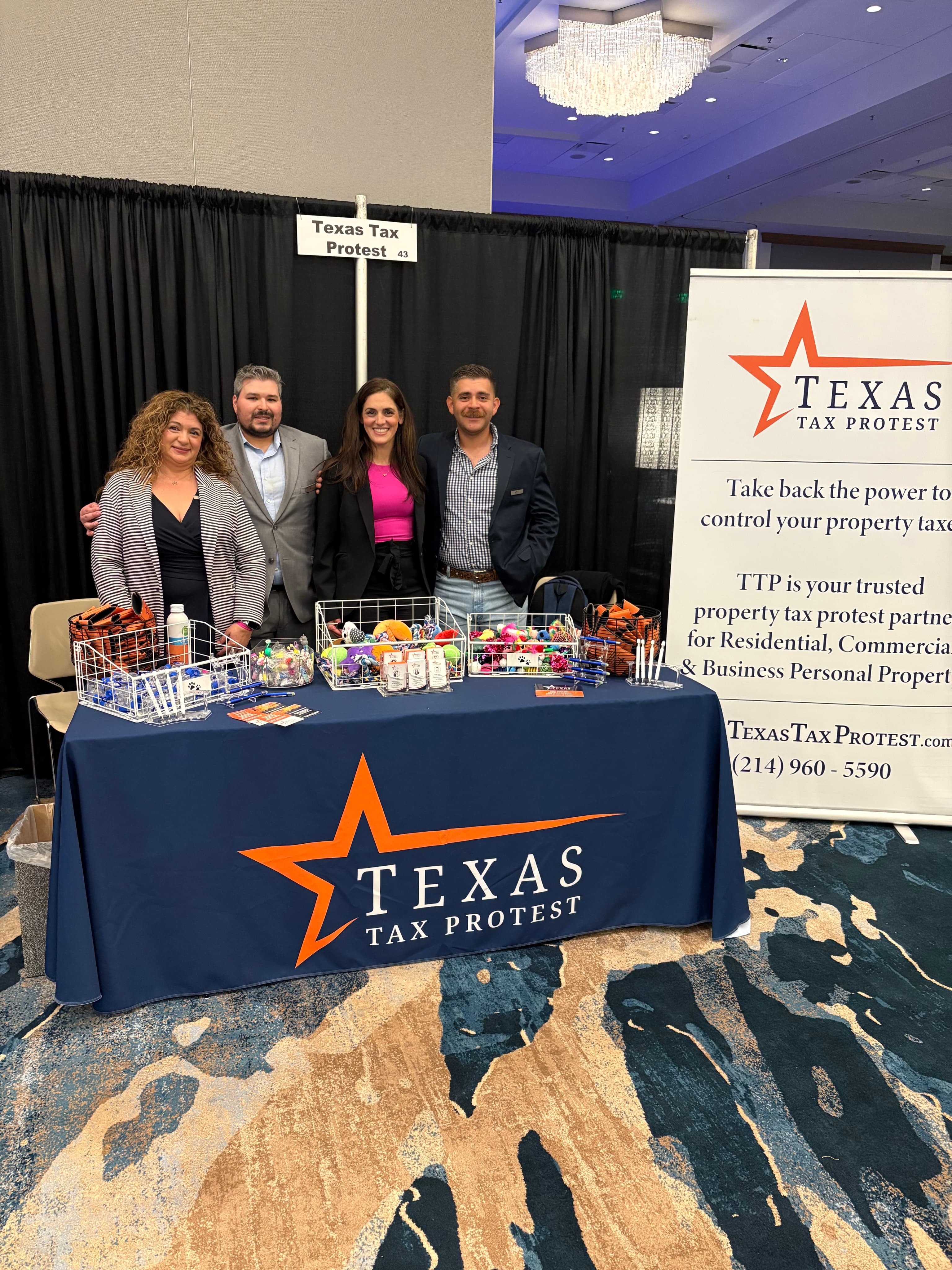 Texas Tax Protest team members standing at their branded event booth with promotional materials and a company banner.