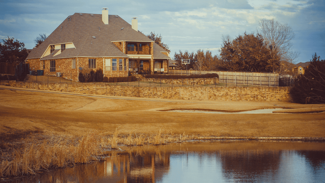 Large red brick house overlooking a nearby pond