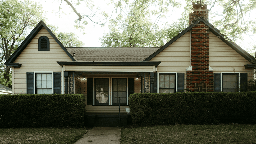 White paneled house with a red-brick chimney.