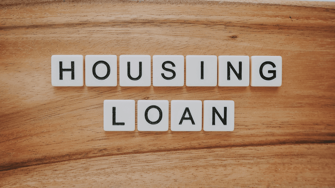 White scramble tiles that spell “housing loan” ontop of a wooden table