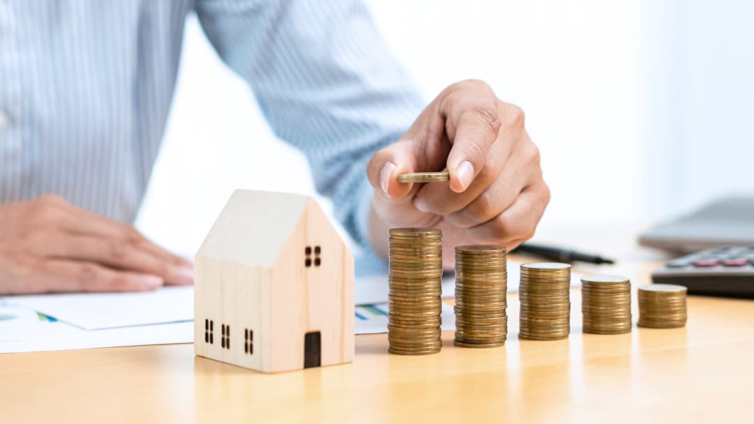 Coin stacks growing beside a house model_ illustrating increasing monthly housing costs